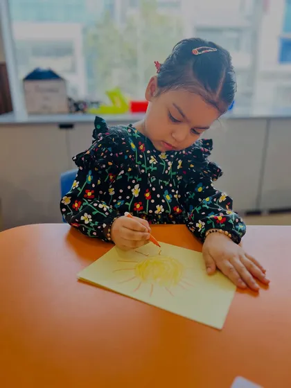 A slightly different angle of the same focused artist. We provide the space and materials for children to let their creativity shine through their drawings.