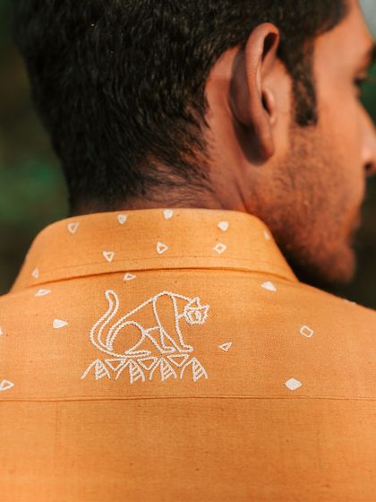 The 'Ferocity' shirt in tangerine orange, with a hand-embroidered panther on the back yoke. Crafted from natural kala cotton, it's for those with a 'Let's get it done' approach.