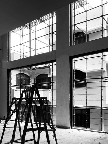 Scaffolding fills the large window frames of a living space in progress, showing the scale of the room and the work being done.