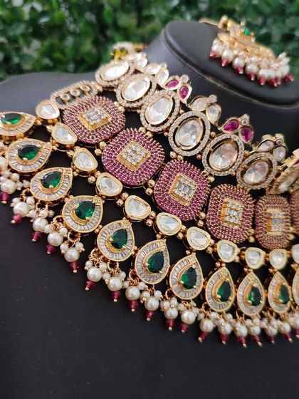 A close-up of the necklace, showing the combination of square and teardrop shapes with pink and green stones.