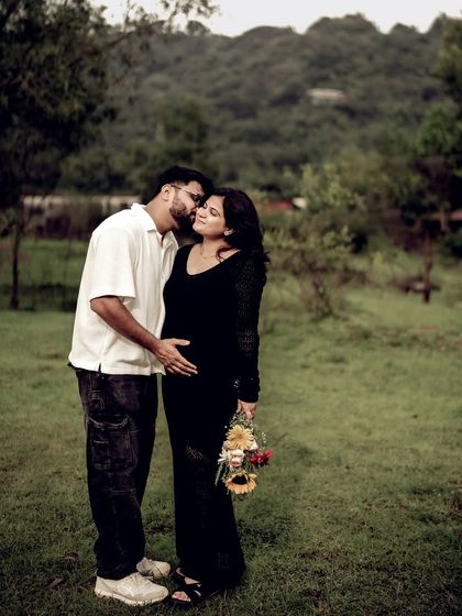 A tender moment in a green field. He kisses her cheek as they embrace, with a bouquet of sunflowers adding a pop of color.