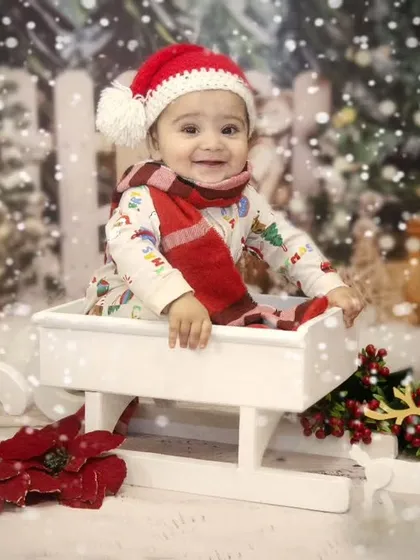 Jingle bells, jingle bells. This little one is enjoying a ride in Santa's sleigh during a fun and festive Christmas-themed sitter session.