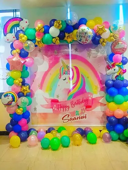 A full view of the rainbow unicorn photo backdrop, with balloons on the floor for kids to play with.