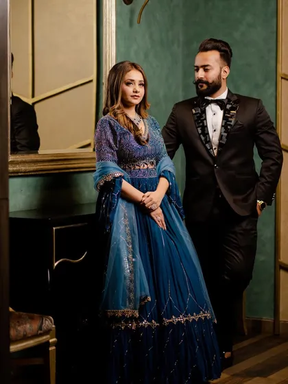 A sophisticated portrait from a cocktail party. The couple's blue and black outfits look stunning against the moody, elegant backdrop.