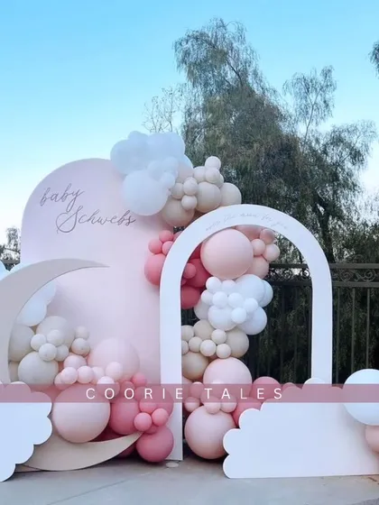 A dreamy outdoor baby shower setup with a "love you to the moon and back" feel. This beautiful arrangement uses soft pinks and whites, with cloud and moon shaped backdrops to create a magical, open-air celebration.