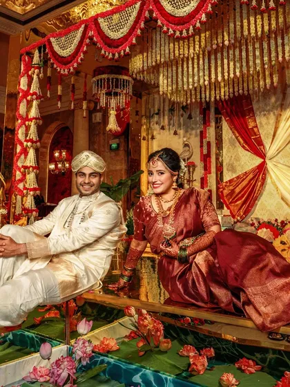 A portrait of regal elegance. I love seeing my couples take center stage within the decor I've crafted for them. Here, the bride and groom are framed by the grandeur of a South Indian inspired setting, with the golden mirror floor reflecting the opulence around them.