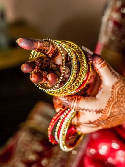 The sound of bangles is the sound of a wedding. This detailed shot focuses on the bride's hands, adorned with henna and colorful bangles, a key part of the getting-ready ritual.