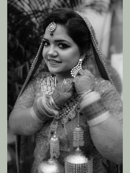 A classic black and white portrait of the bride. Her smile and the way she adjusts her earring create a candid and charming image.