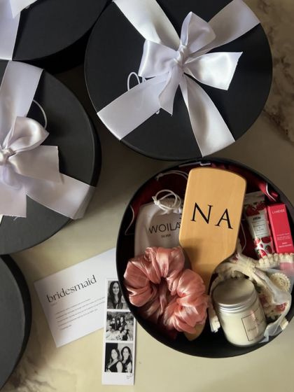 This bridesmaid hamper is all about pampering. It includes a personalized hairbrush, a satin scrunchie, a scented candle, and a custom photo strip to capture your favorite memories.