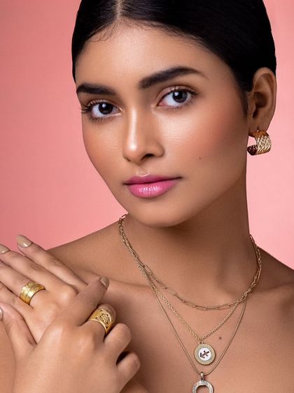 A direct and confident portrait, showcasing how minimal gold accessories can make a powerful statement.