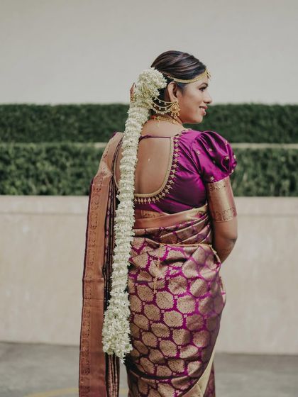 A beautiful back profile showcasing the intricate details of a South Indian bridal look, from the puff-sleeved blouse to the long, fragrant mallige braid.