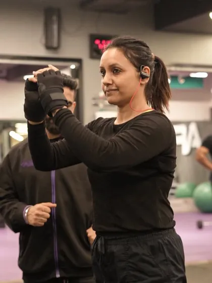 A trainer offers encouragement and form correction to a member during her workout, showcasing the supportive environment we foster.