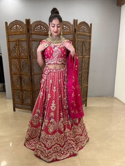 This view shows the full bridal look, with the model styled in a beautiful updo and statement jewelry that complements the pre-loved pink lehenga perfectly.