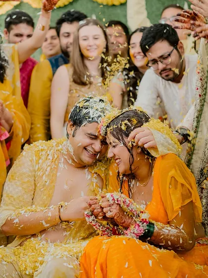 An intimate and joyful moment as the couple is showered with flowers during their Haldi. Their happy embrace says it all.