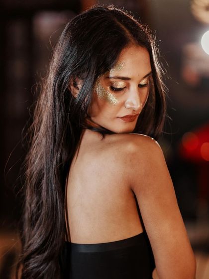 A soft and elegant profile shot. The glitter on her skin catches the light beautifully, creating a magical and romantic feel.