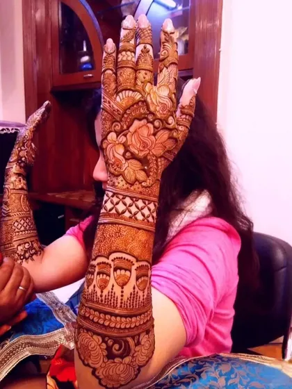 A side view of a full-arm bridal mehendi application in progress. This shows the extent of the coverage, with detailed floral and geometric patterns extending all the way up the arm.