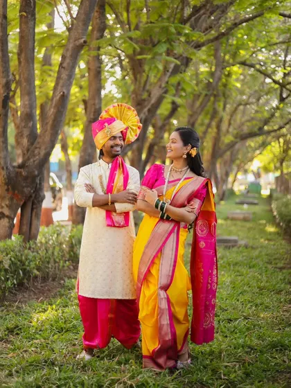A candid moment of laughter during an outdoor pre-wedding shoot. Dressed in stunning Maharashtrian attire, this full-length shot captures the couple's joyful connection amidst a beautiful park setting.