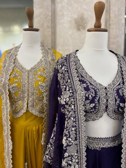 A duo of modern lehenga sets with intricately embroidered jackets. The yellow and deep purple outfits offer a contemporary yet regal look for any celebration.
