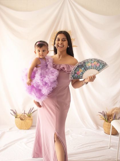 A mother and daughter in matching lavender tones. The mother's joyful expression as she holds her little one is beautiful.