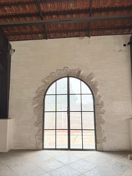 A unique detail from one of our projects. We created a faux stone archway around this large window, adding architectural character to a plain wall using only texture and paint.