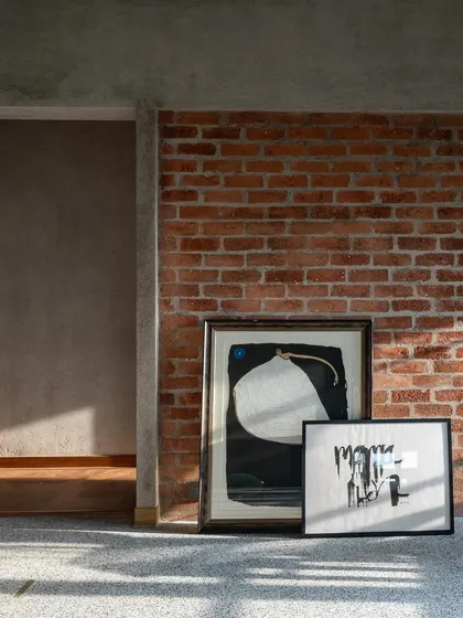 Art leaning against an exposed brick wall in the '9PM' project. This composition of raw texture, modern art, and terrazzo flooring encapsulates our design approach of layering materials and stories to create soulful spaces.