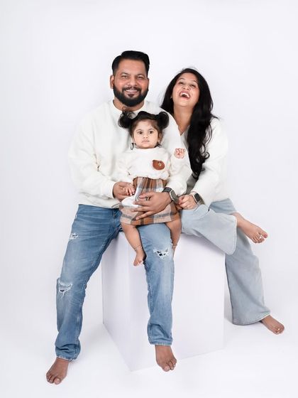 This candid moment of laughter during a studio session is what it's all about. The clean white background keeps the focus on the family's joyful interaction.
