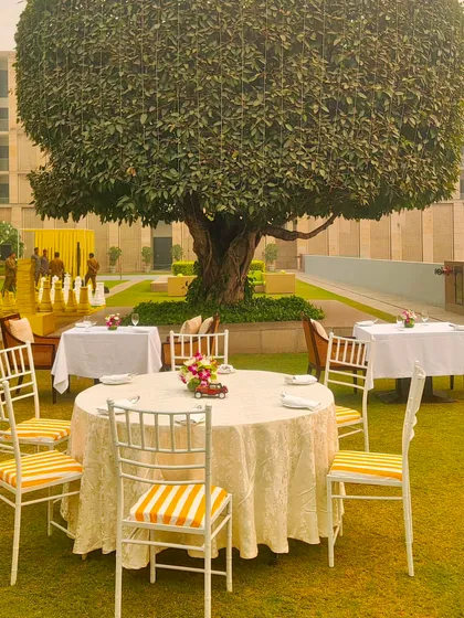 A lovely dining table set under a large tree at the brunch event. The yellow and white striped chair cushions tie the whole theme together beautifully.
