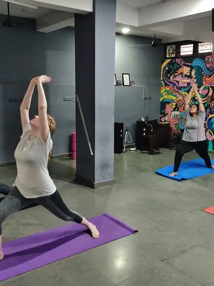 The energy in our group classes is amazing. Here we are moving through Virabhadrasana I (Warrior I pose), a foundational asana that builds strength in the legs and opens the chest. I provide guidance to ensure proper alignment for everyone.