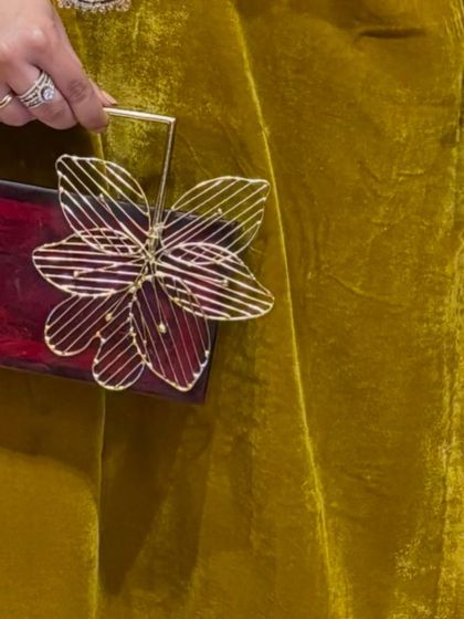 Accessorizing is key. This unique floral-handled clutch adds a touch of modern artistry to the traditional velvet outfit.
