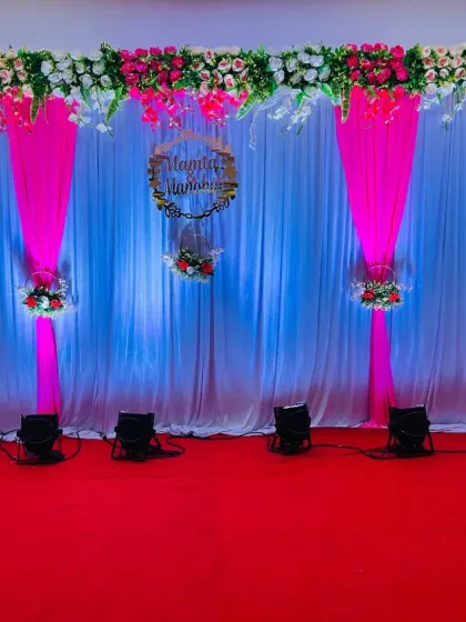 An elegant engagement stage with a white and pink drape backdrop. The decor is accented with floral arrangements and spotlights for a sophisticated look.
