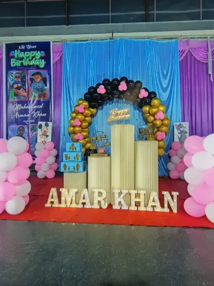A first birthday celebration at Milan Convention Hall in Shivamogga. We included a custom photo banner along with a black and gold balloon arch and light-up letters for the name 'AMAR KHAN'.