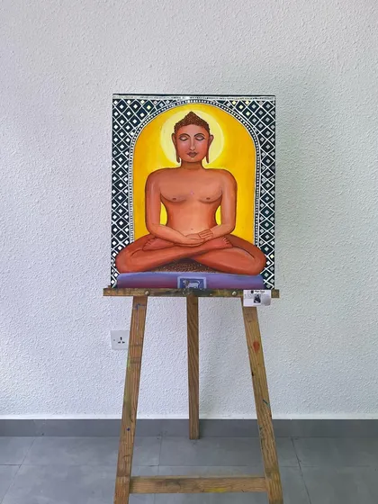 The Mahavir Swami painting displayed on an easel. The combination of traditional imagery with mixed-media techniques like Lippan art makes it a unique piece for any home.