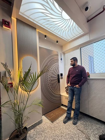 A grand entrance at Nirala Estate, featuring a custom door with intricate CNC carving, a backlit ceiling, and elegant wall paneling.