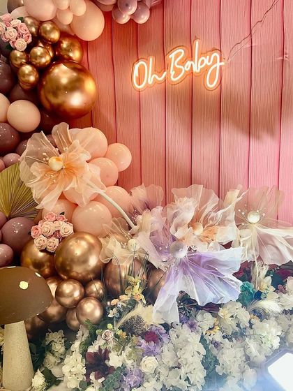 The "Oh Baby" neon sign glows against the pink shiplap backdrop, surrounded by delicate organza flowers and a cascade of balloons. This shows how I use lighting and texture to create a dreamy effect.