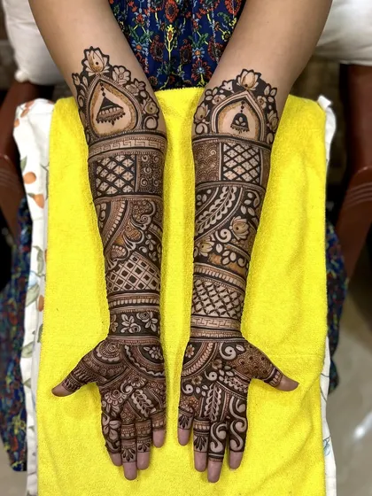 This bridal design features hanging bells (jhumkas) and architectural domes. The geometric patterns on the arms add a modern touch to the traditional motifs.