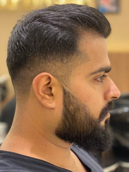 A side profile of an extraordinary men's haircut, featuring a perfect fade and a well-groomed beard.
