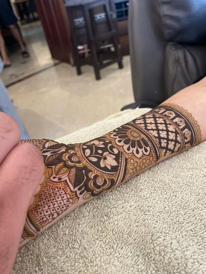 A close-up of a detailed forearm band. This section of the mehandi features lotuses, checks, and paisleys, all done with very fine lines.