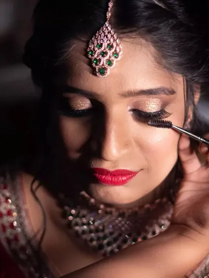 A close-up of the makeup application for the Sangeet. I'm applying mascara to her lower lashes to make her eyes pop, complementing the gold eyeshadow.