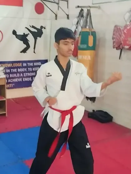 A red belt student executing a powerful block during his black belt test. The test evaluates not just forms, but also power, focus, and technique.