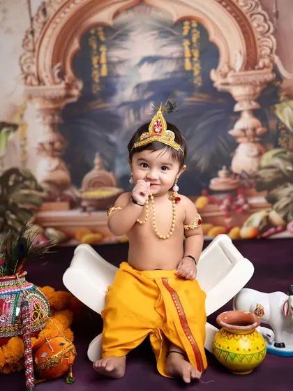 A cheeky pose from our little Krishna, looking right at the camera. The outfit and props come together to create an adorable and authentic look.