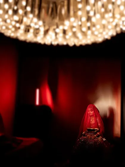 A dramatic and artistic shot of a bride during a wedding ritual. The deep red lighting and mysterious atmosphere create a powerful and unique image.
