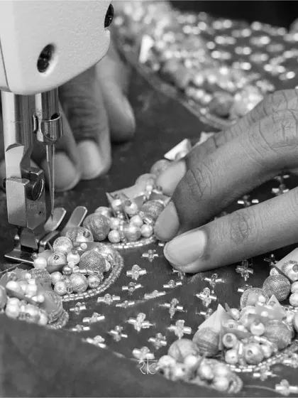 The soul of couture lies in the hands of the artisan. Here, every bead and sequin is meticulously stitched by hand, a patient process that transforms fabric into a work of art. This is the essence of our handcrafted promise.