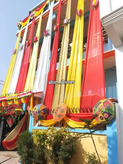 This home decoration uses a classic combination of red, yellow, and white drapes. I also added decorative Rajasthani umbrellas to the balcony for an extra traditional touch.