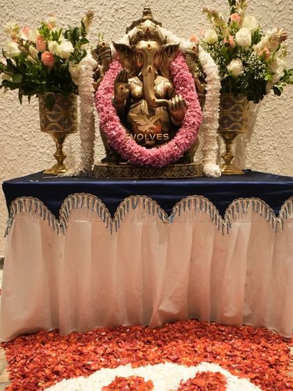 A beautifully arranged table for the Ganesha idol at a house warming, complete with floral bouquets and a decorative table skirt.