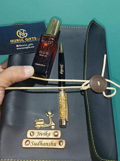 A thoughtful gift combo of a personalized leather thread diary, a name pen, and a bottle of perfume.
