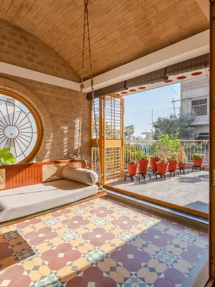 Another view of the beautiful swing and lounge area, showing how it opens up to the terrace filled with potted plants.