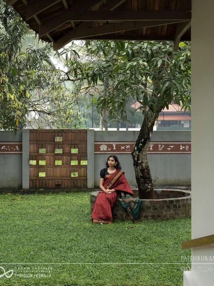 The garden of the 'Paithrukam' residence, with its central tree and traditional wall detailing, provides a serene and picturesque setting.