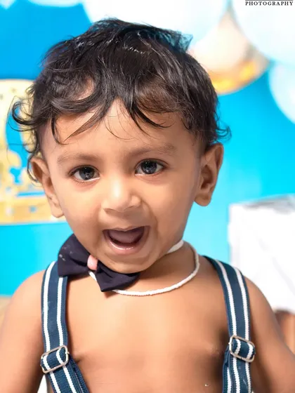 A little prince celebrating his first birthday with a royal blue cake smash. The setup includes a crown, balloons, and a delicious-looking cake ready to be smashed.