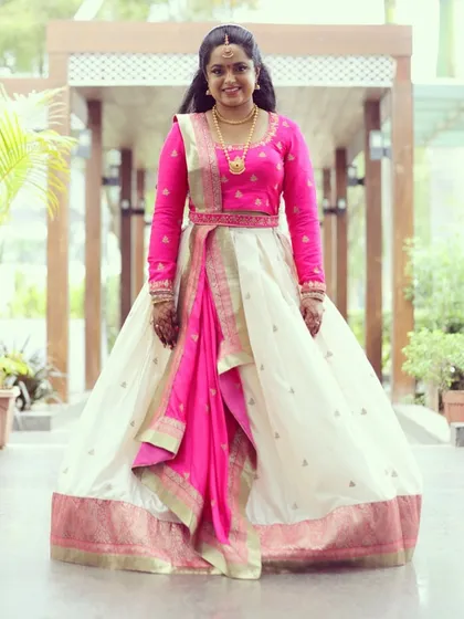 Deepika looks stunning in this custom-designed half saree. I paired a simple, elegant off-white skirt with a vibrant pink long-sleeved blouse and a matching draped dupatta.