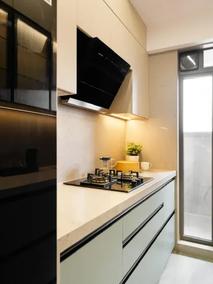 A close-up of the cooking zone, showing the sleek black chimney and hob set against a neutral backsplash. The handleless drawers maintain the kitchen's minimalist aesthetic.